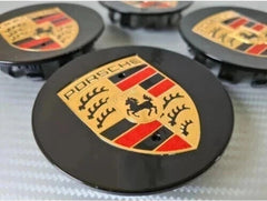 Eliteridegear Porsche wheel centre caps in black and gold, featuring a sleek design for stylish vehicle accents.