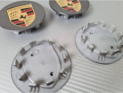 Grey Porsche wheel centre caps by Eliteridegear, featuring a sleek design and official Porsche branding.