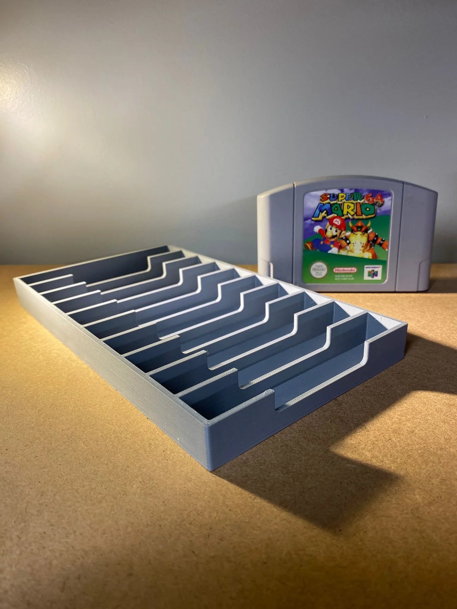 Game Display N64 game storage case holding 12 Nintendo 64 cartridges with visible game labels and clear plastic compartments.