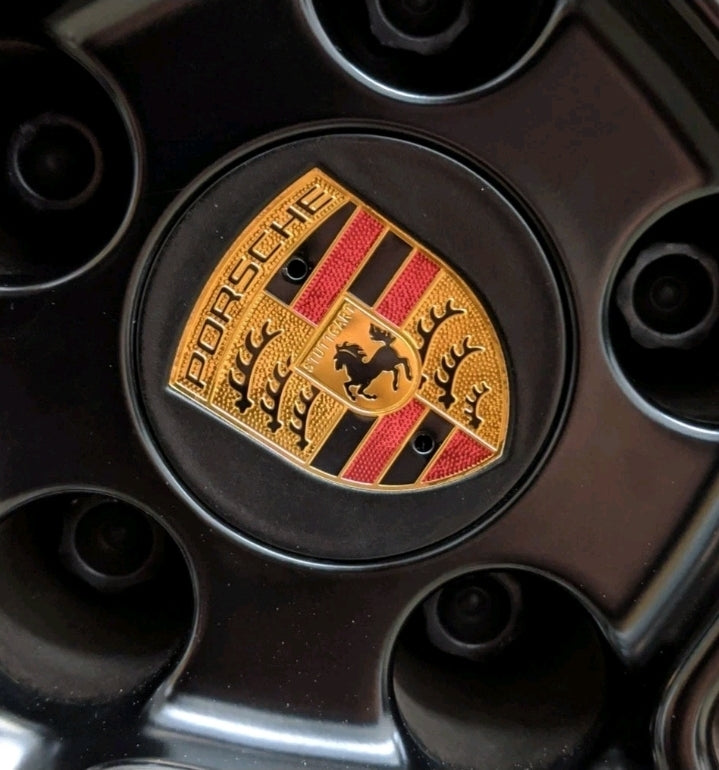 Black and gold Porsche wheel centre caps by Eliteridegear, featuring a sleek design and the Porsche logo in the center.