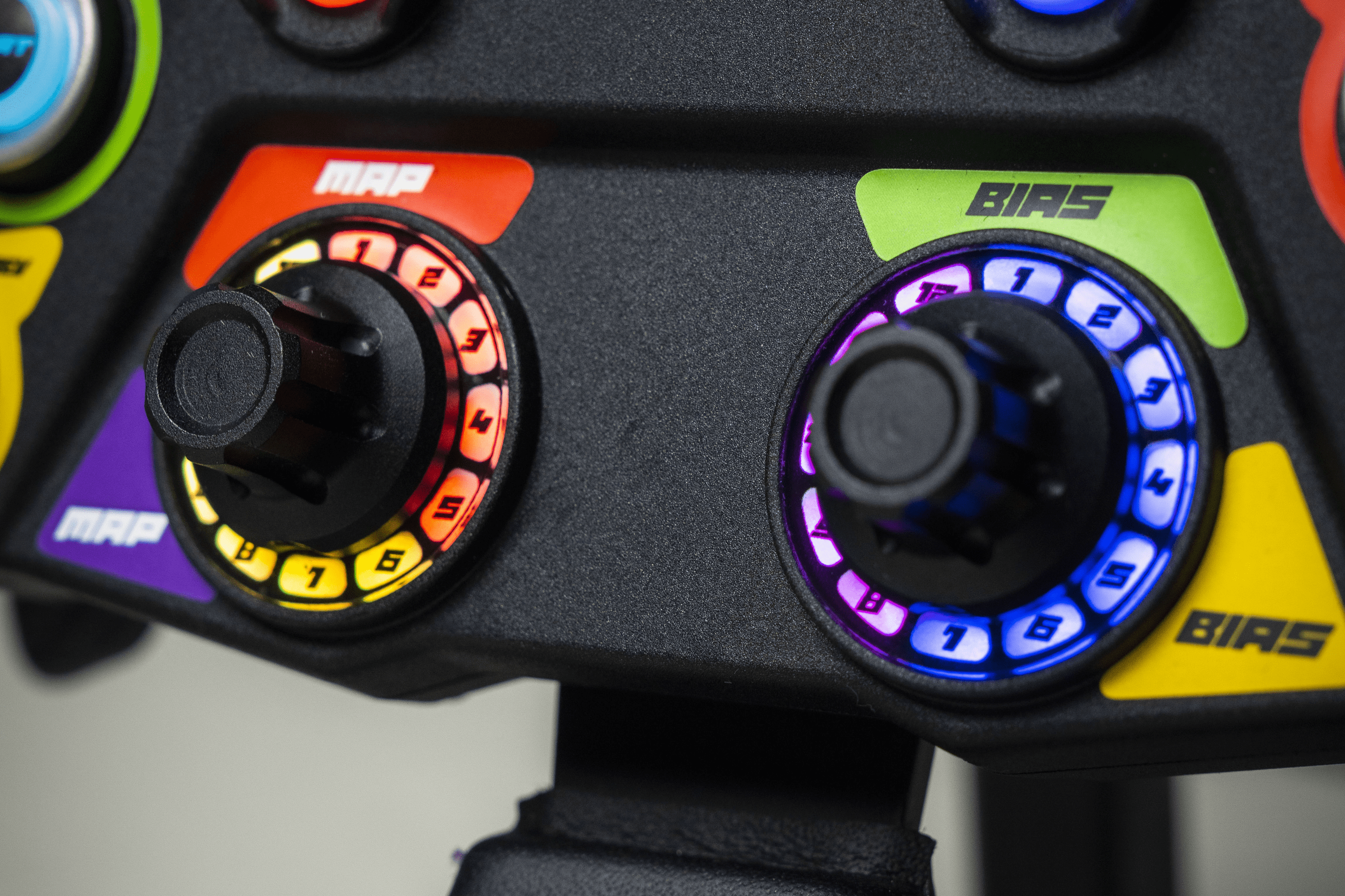 Close-up of Trak Racer UK Conspit 310 APEX steering wheel with rotary encoders and control buttons for racing simulation.