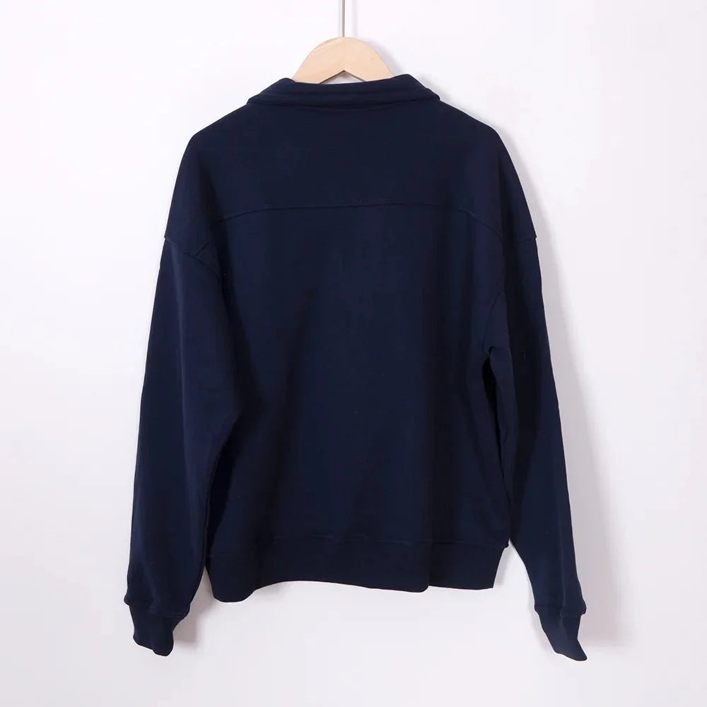Women’s ZESSAM Club Graphic Sweatshirt by Adistore featuring long sleeves and a collared design, displayed on a hanger.