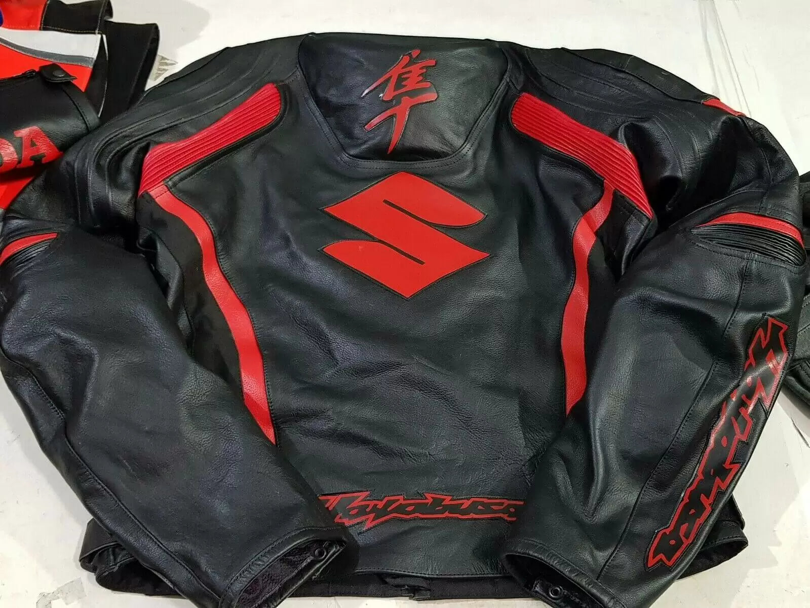 Suzuki Hayabusa red and black motorcycle jacket by DAMOTOGEAR, showcasing durable textile material and protective armor features.
