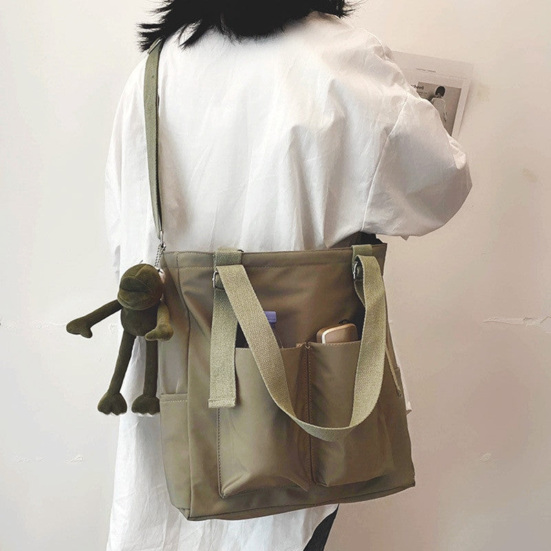 Adistore women's shopper bag with zippered main compartment, crossbody strap, and tote shoulder handle in solid design.