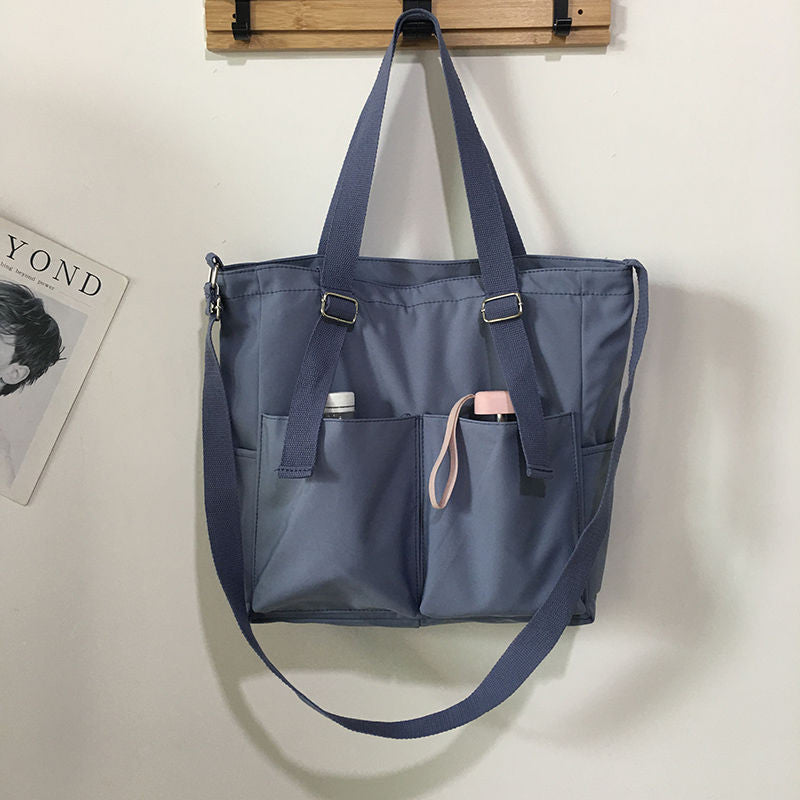 Adistore women's shopper bag with zippered solid design, featuring a crossbody and tote shoulder bag, shown in black.